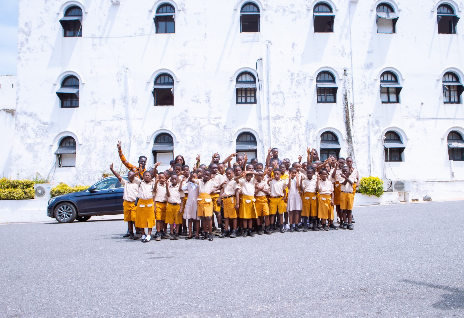 School community group posing happily in front of campus building